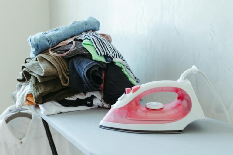 Ferro de passar roupa sobre pilha de roupas organizadas em casa