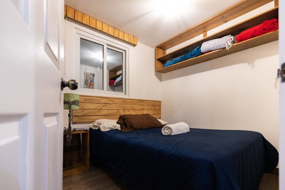 Quarto pequeno organizado com prateleiras de madeira e cama confortável - truques para otimizar espaço