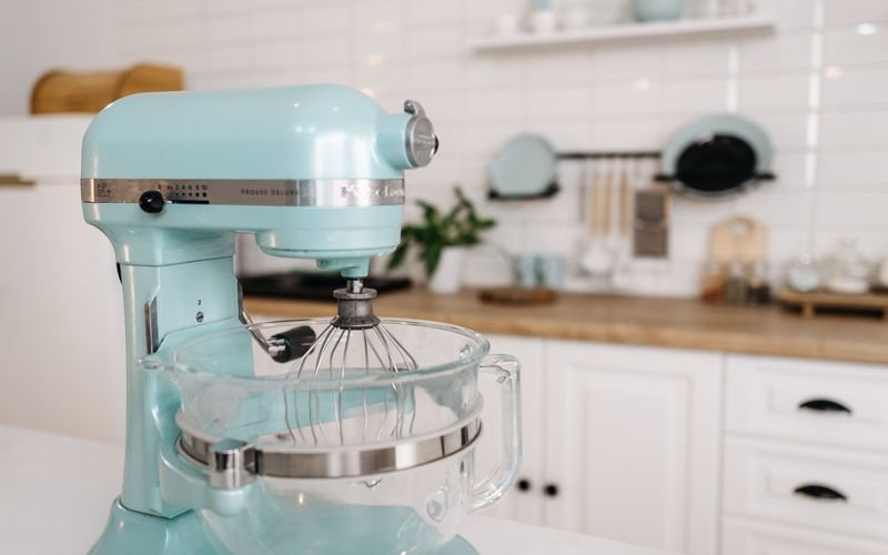 Batedeira planetária em ambiente de cozinha com utensílios de panificação