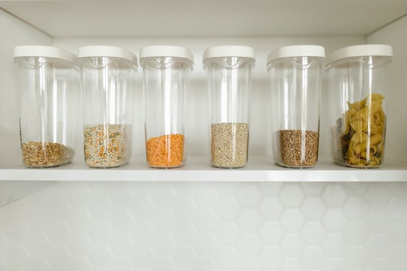 Containers pl sticos organizados em prateleira de despensa com alimentos diversos