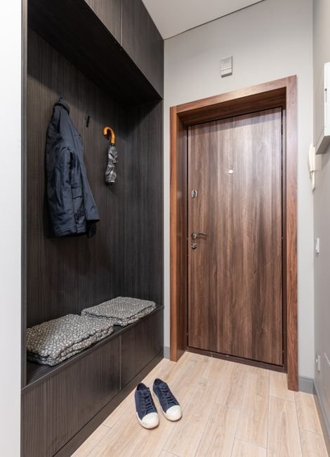 Hall de entrada com armário de madeira, casacos pendurados, guarda-chuva e sapato no chão
