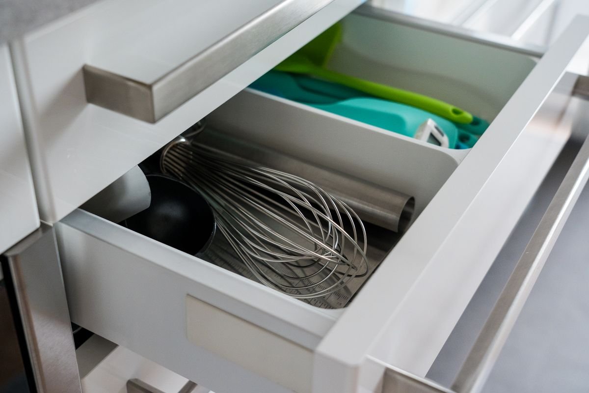 Gaveta de cozinha com divisórias e utensílios organizados em cestos brancos