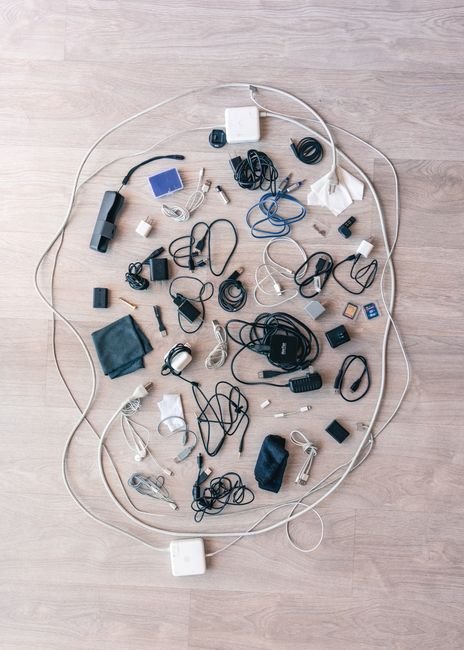 Cabos, fios e carregadores espalhados antes da organizacao em flat lay