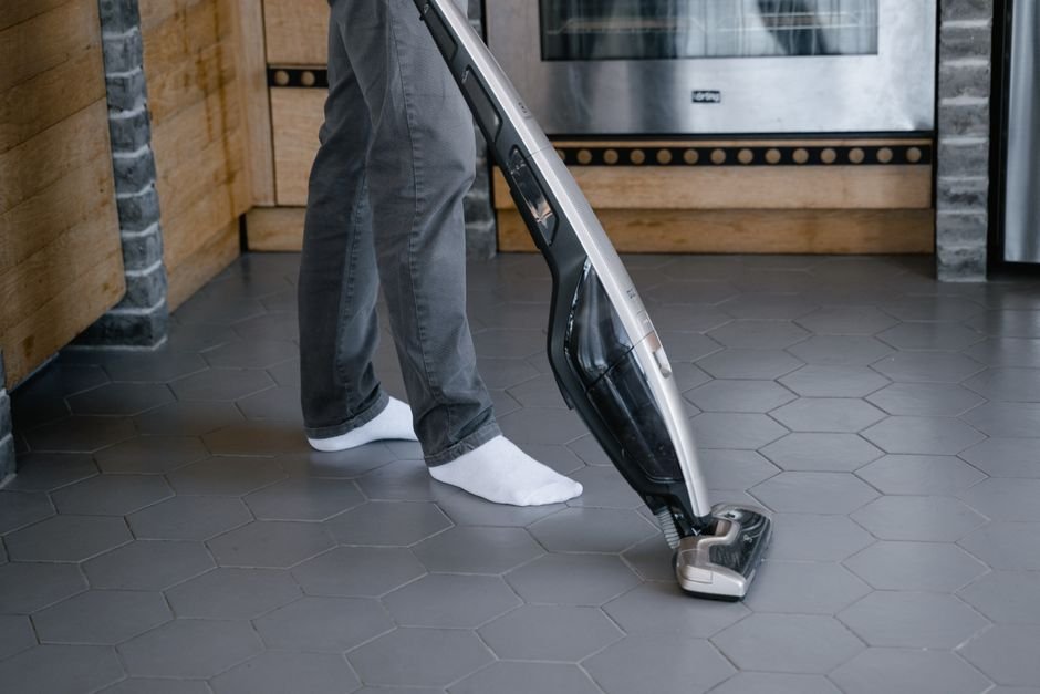 Aspirador de pó vertical moderno e sem fio sendo usado em sala de estar limpa