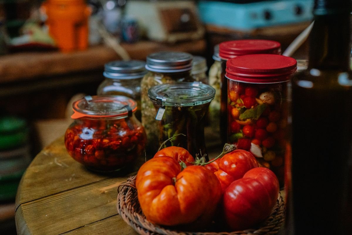 Pote de vidro com catchup caseiro vermelho, fresco e sem conservantes ao lado de tomates maduros