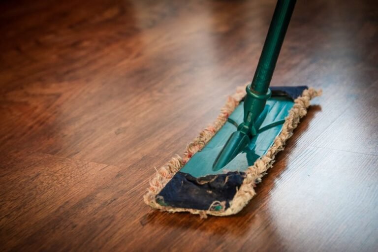 Mop passando pano sobre piso vinilico claro durante a limpeza da casa