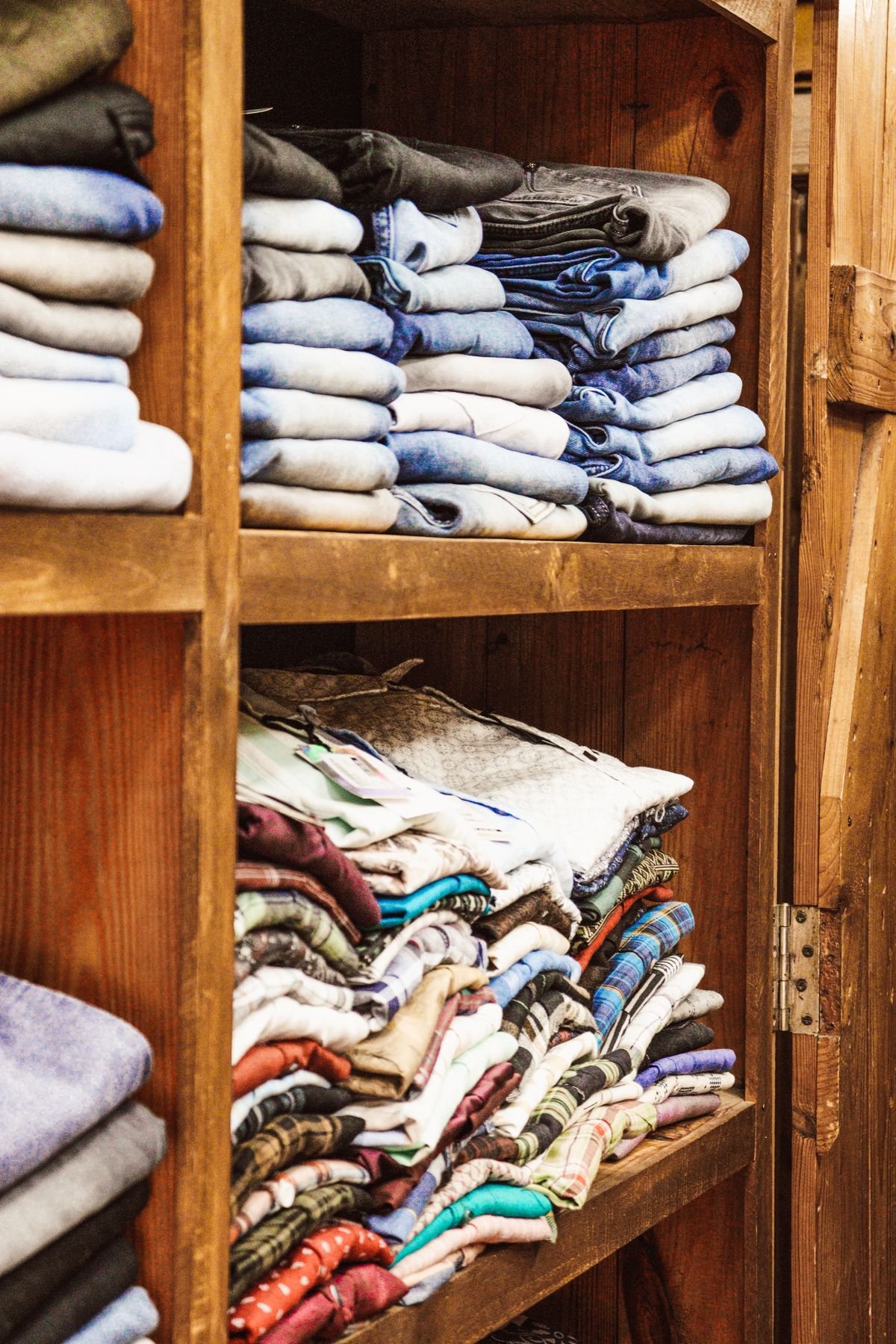 Roupas dobradas e organizadas em prateleiras de madeira