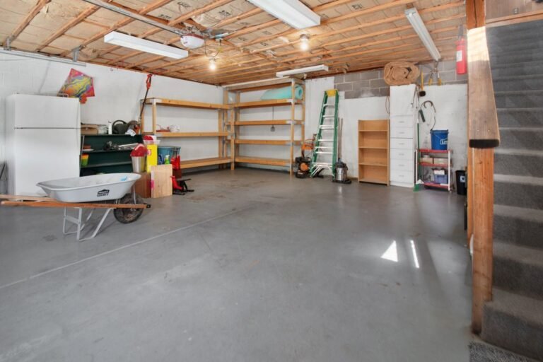 Garagem residencial ampla com prateleiras de madeira, freezer, carriola e armarios para organizacao