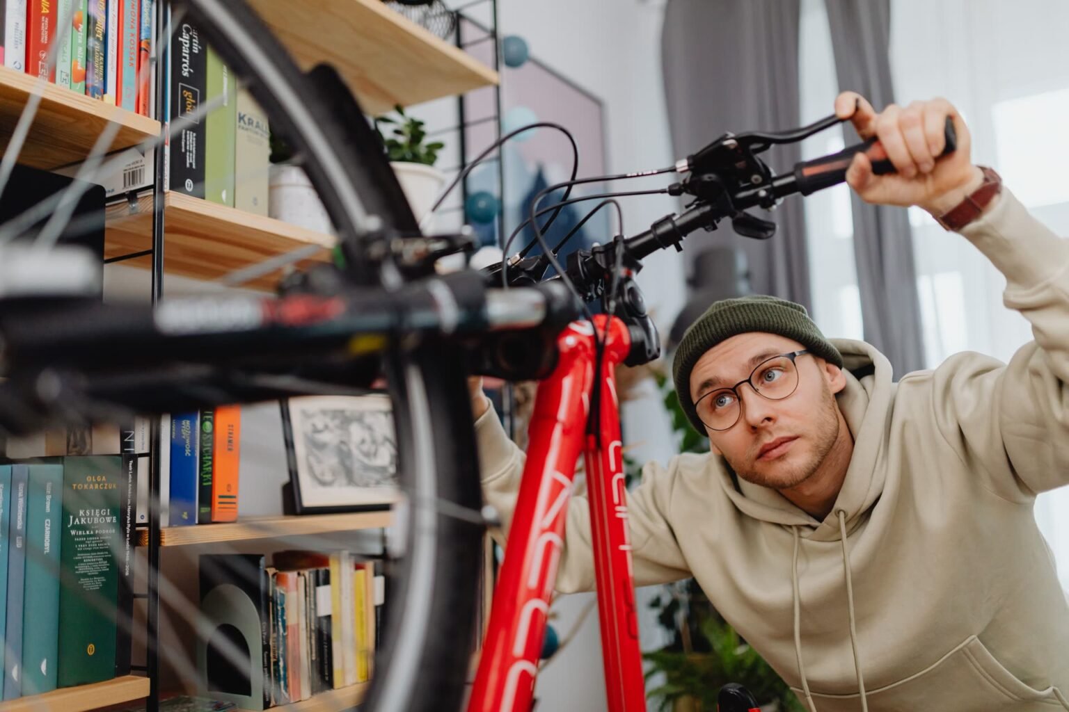 Pessoa fazendo a manutenção da bicicleta dentro de casa antes de guardá-la no suporte: como guardar bicicleta em apartamento sem sujar a parede