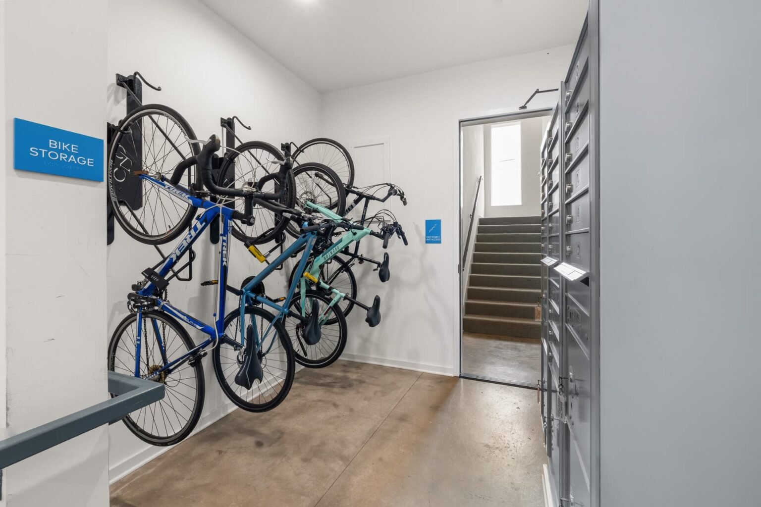 Bicicletas presas em suportes de parede em um bicicletário interno organizado: como guardar bicicleta em apartamento usando ganchos fixos