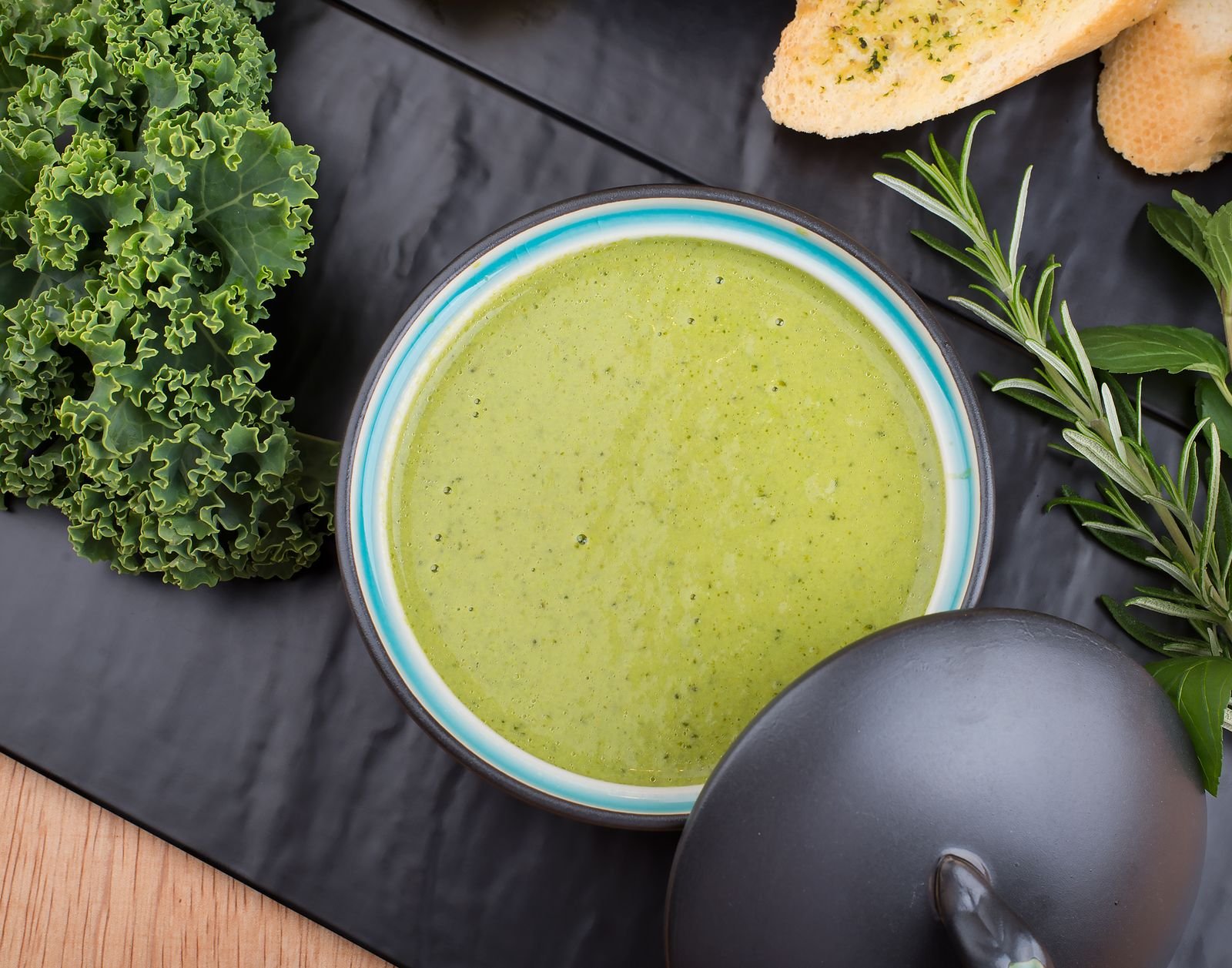 Caldo verde caseiro cremoso servido em tigela com couve manteiga e ervas frescas ao lado