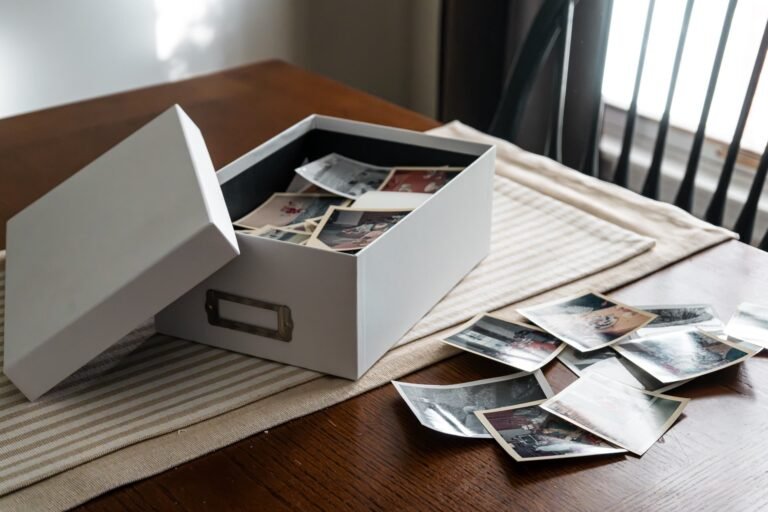 Caixa aberta com fotos antigas de família sobre mesa de madeira: como organizar fotos e lembranças em casa