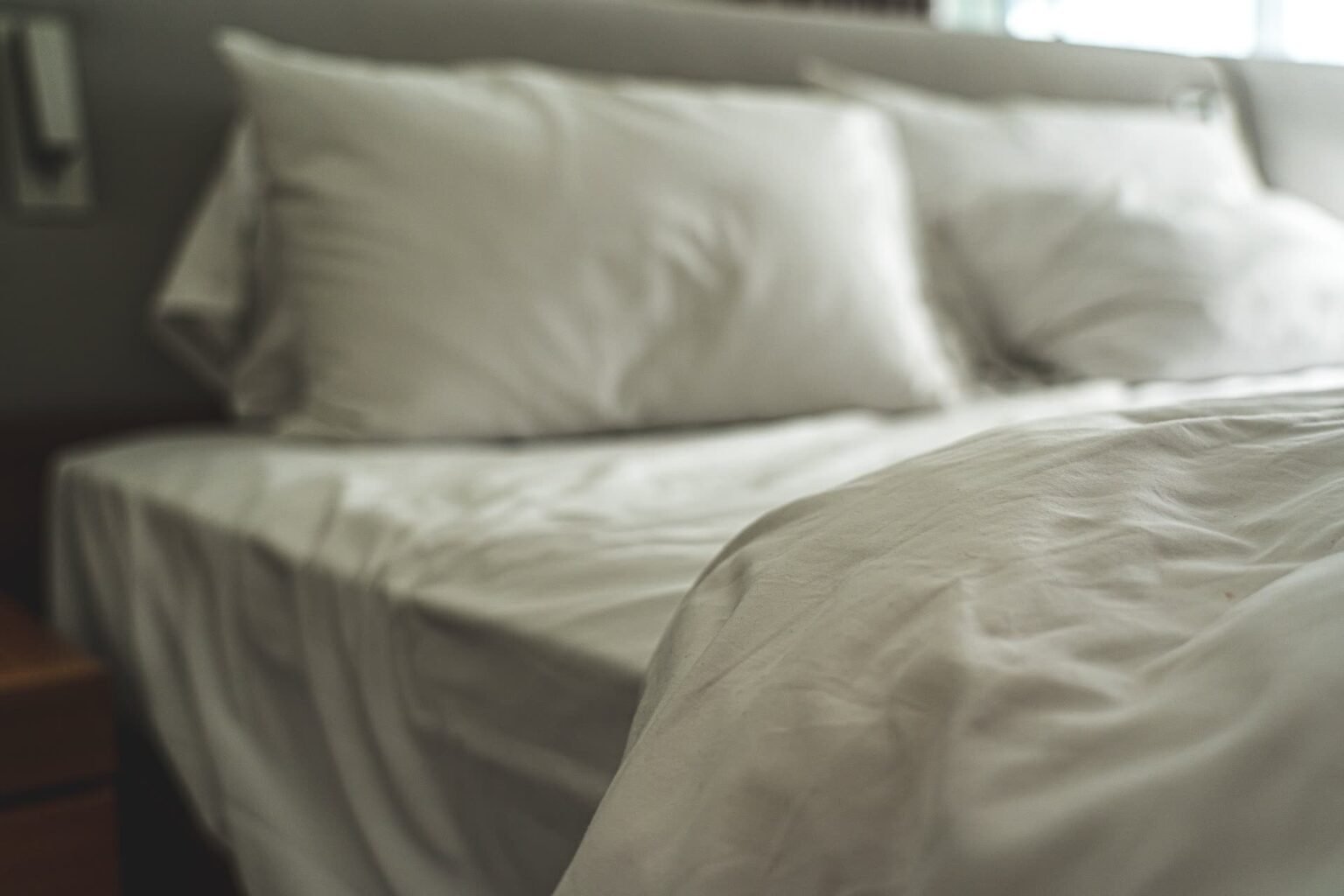 Cama de casal arrumada com jogo de cama branco e travesseiros macios: como escolher o tamanho, o tecido e a contagem de fios certos