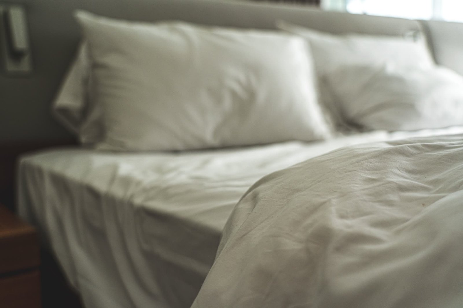 Cama de casal arrumada com jogo de cama branco e travesseiros macios: como escolher o tamanho, o tecido e a contagem de fios certos