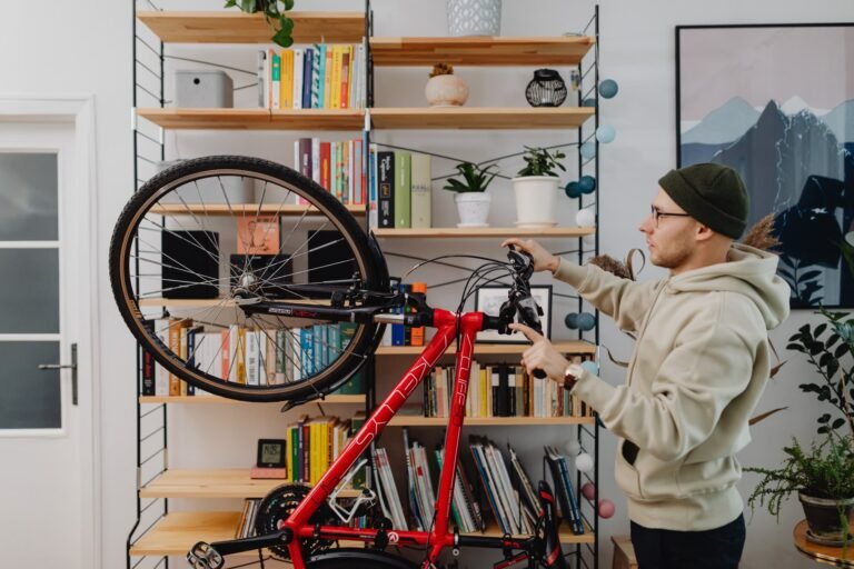 Bicicleta apoiada dentro de apartamento ao lado de estante de livros: como guardar bicicleta em apartamento sem ocupar a sala