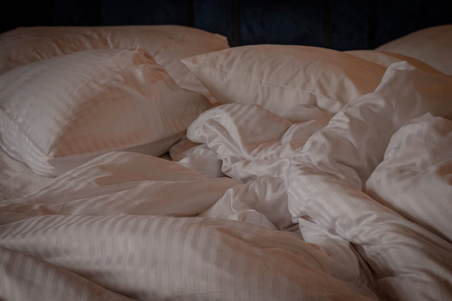 Edredom branco sobre cama de casal, com travesseiros e roupa de cama dobrada: como lavar edredom em casa sem empelotar