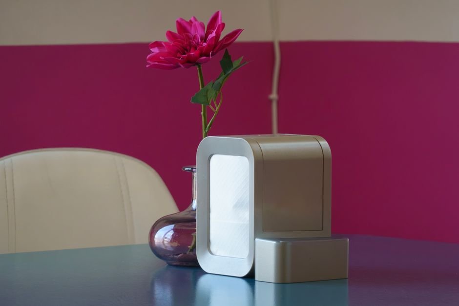 Purificador de ar moderno e minimalista sobre mesa azul com flor rosa em sala decorada