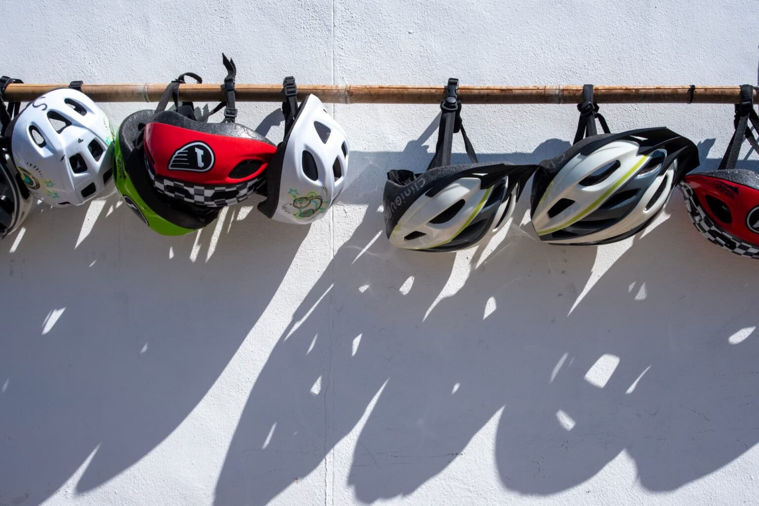 Capacetes de bicicleta pendurados em ganchos na parede formando um painel organizado: como guardar bicicleta em apartamento com os acessórios