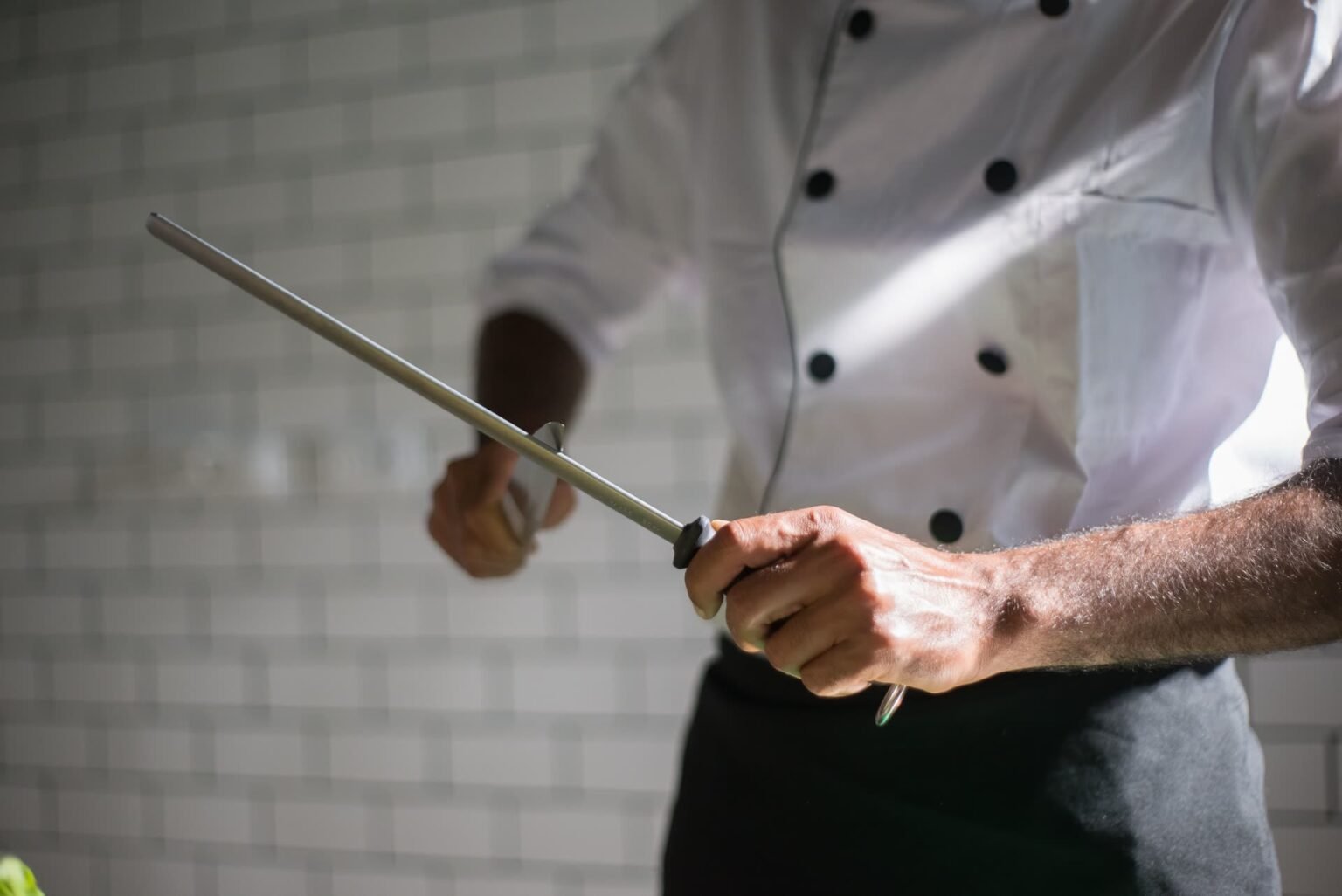Chef passando a chaira na faca em ângulo baixo: como afiar faca com chaira é manutenção do fio, não substitui a pedra