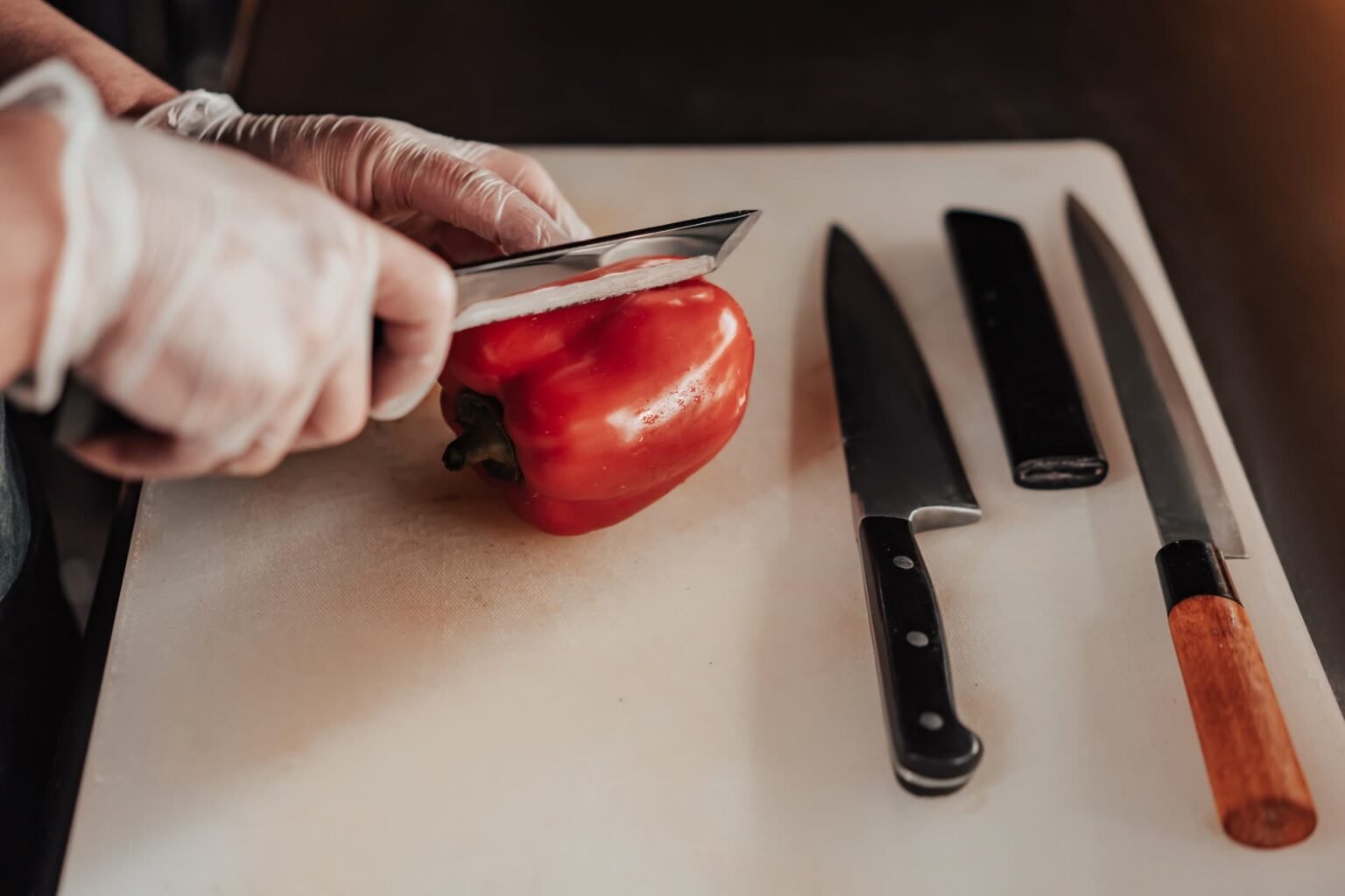 Faca afiada cortando pimentão em tábua de corte: como afiar faca em casa para fatiar sem amassar os alimentos