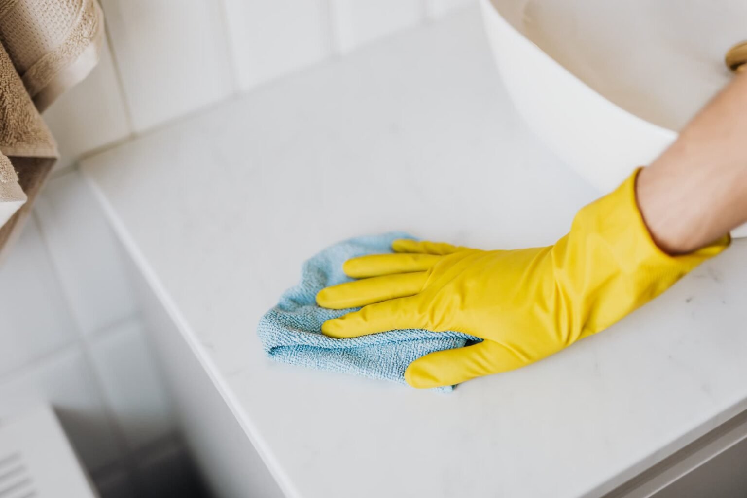 Pano de microfibra e luva amarela limpando bancada de mármore branco de banheiro: como limpar granito e mármore com pH neutro