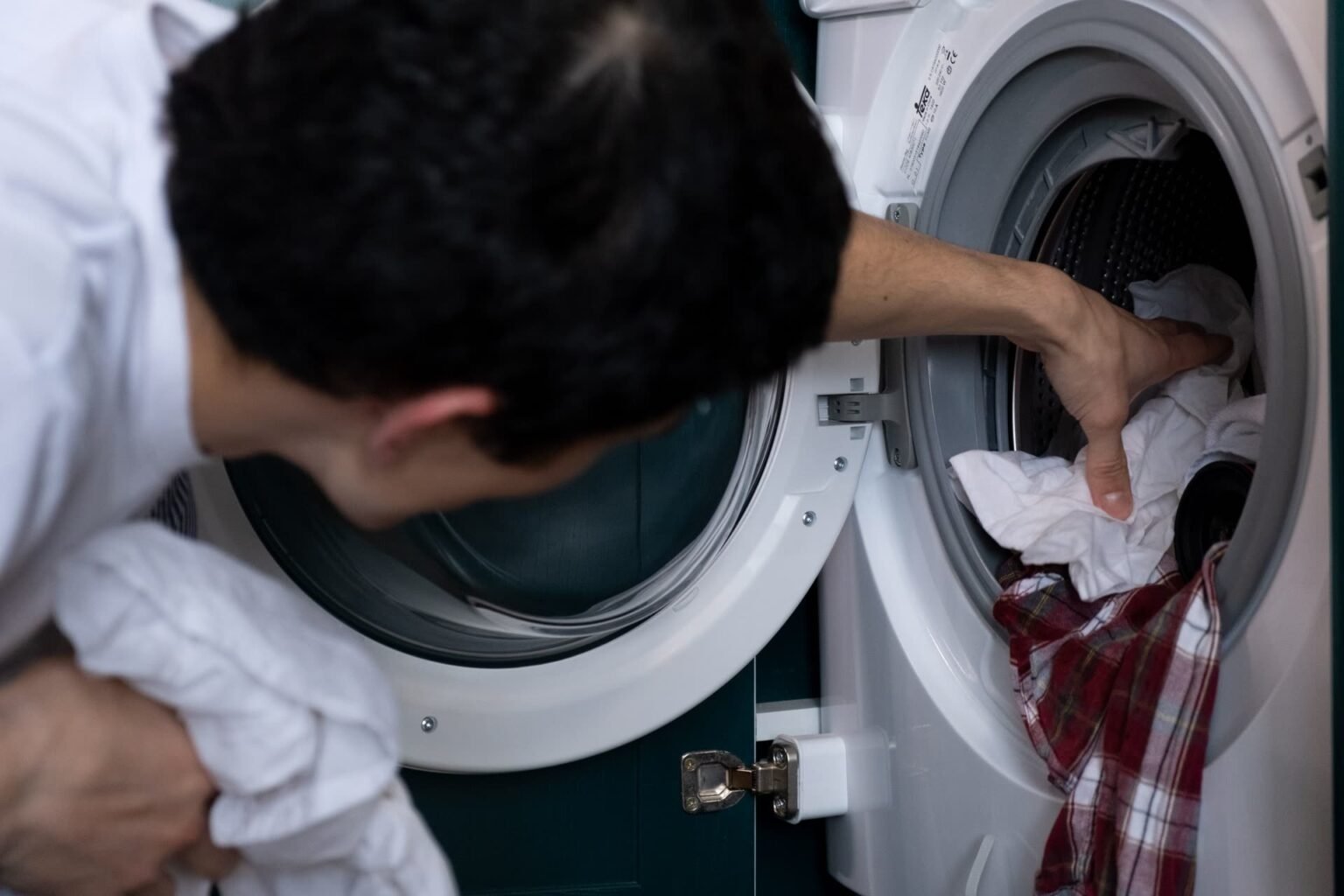 Roupa sendo colocada em máquina de lavar: como lavar edredom na máquina sem sobrecarregar o tambor