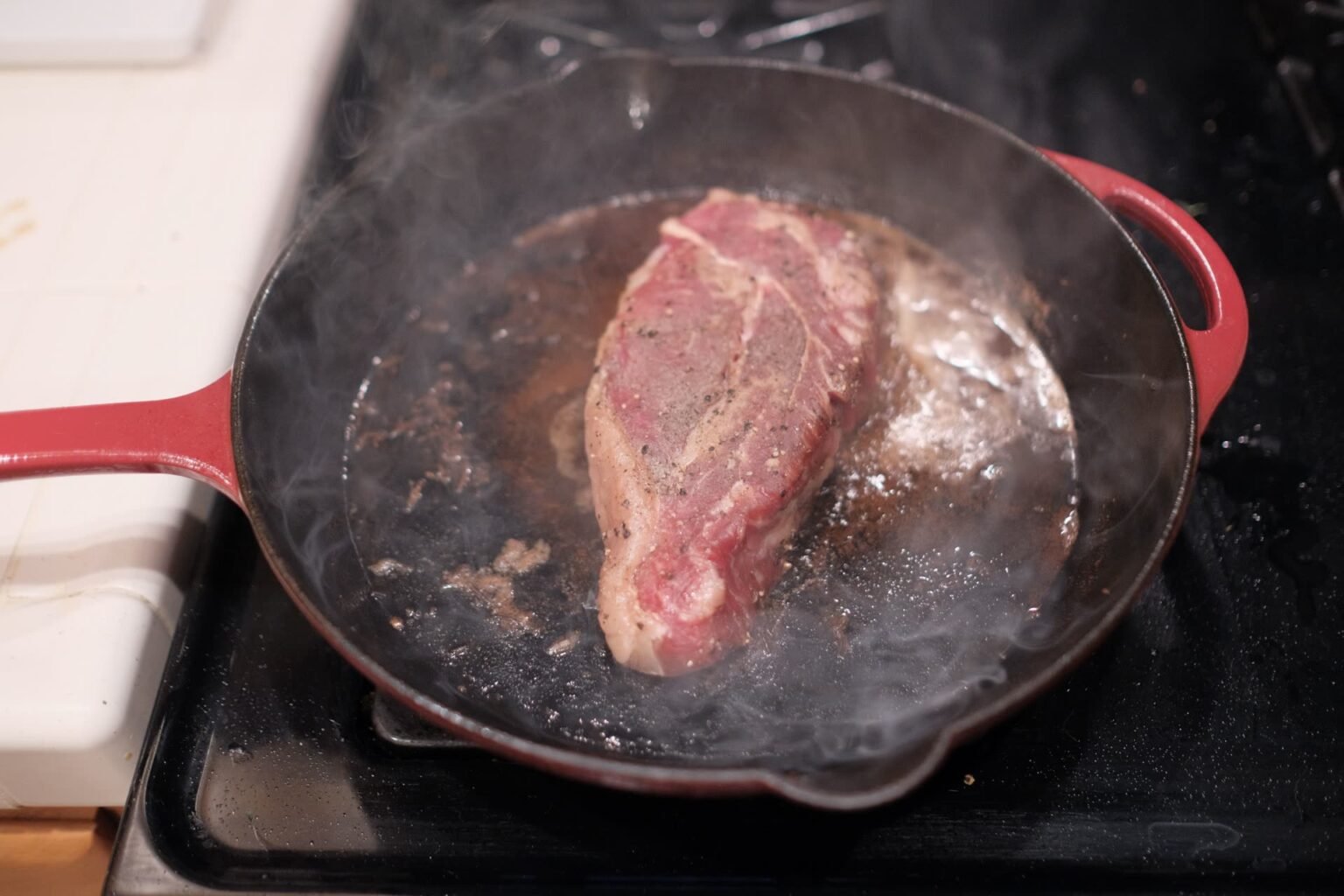 Bife selando em frigideira de ferro fundido no fogão, com fumaça e crosta dourada: como usar panela de ferro fundido no dia a dia