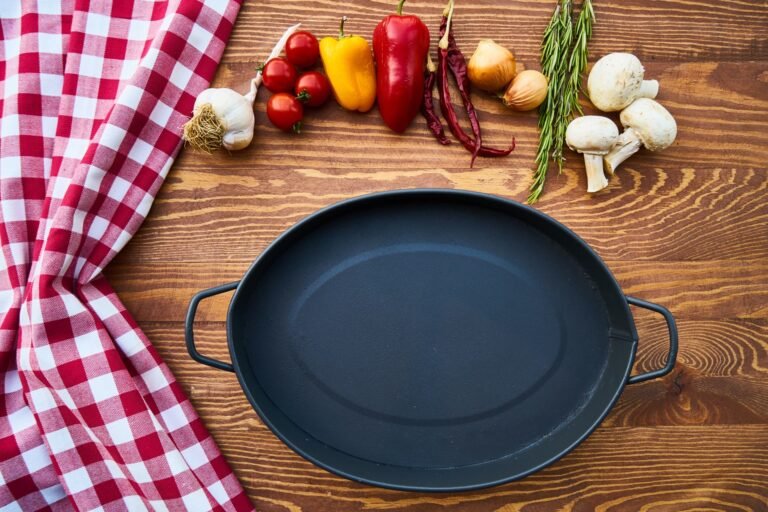 Panela de ferro fundido vazia sobre mesa de madeira com ingredientes frescos ao redor: como temperar panela de ferro fundido em casa