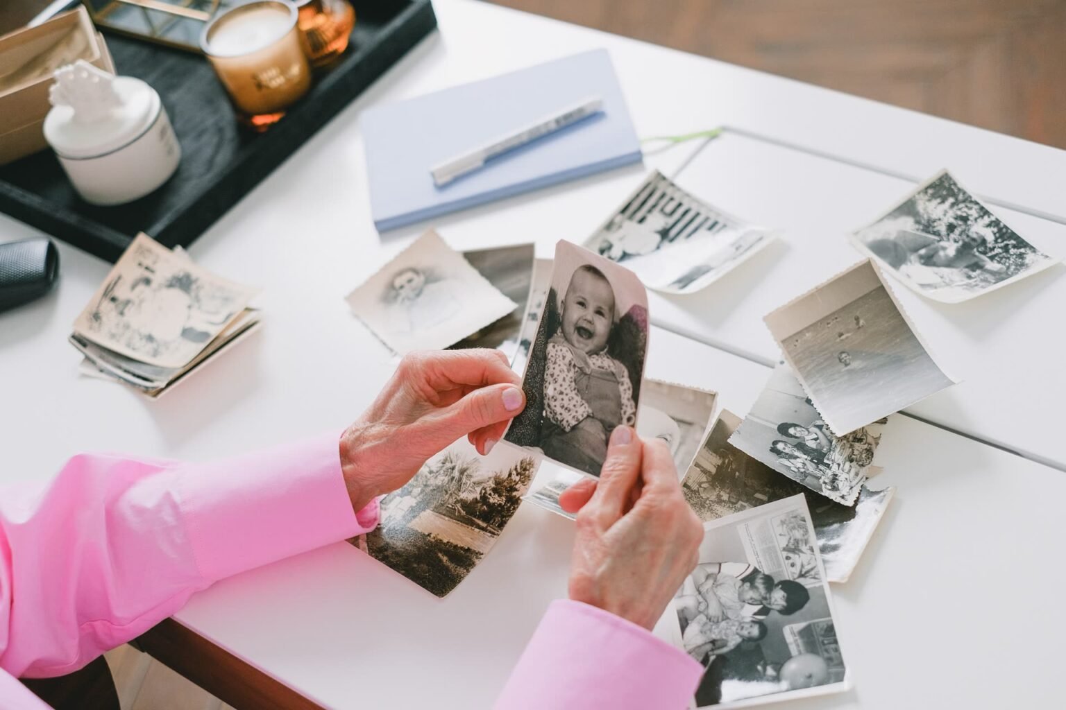 Mãos separando fotos antigas de família sobre a mesa: como organizar fotos e lembranças em casa